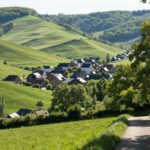 Paysage belge paisible avec collines vertes et village pittoresque.