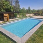 Piscine construite dans un jardin belge ensoleillé.