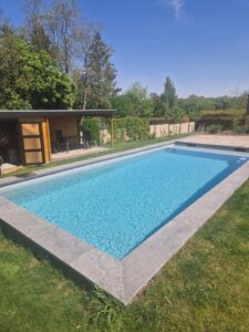Piscine construite dans un jardin belge ensoleillé.